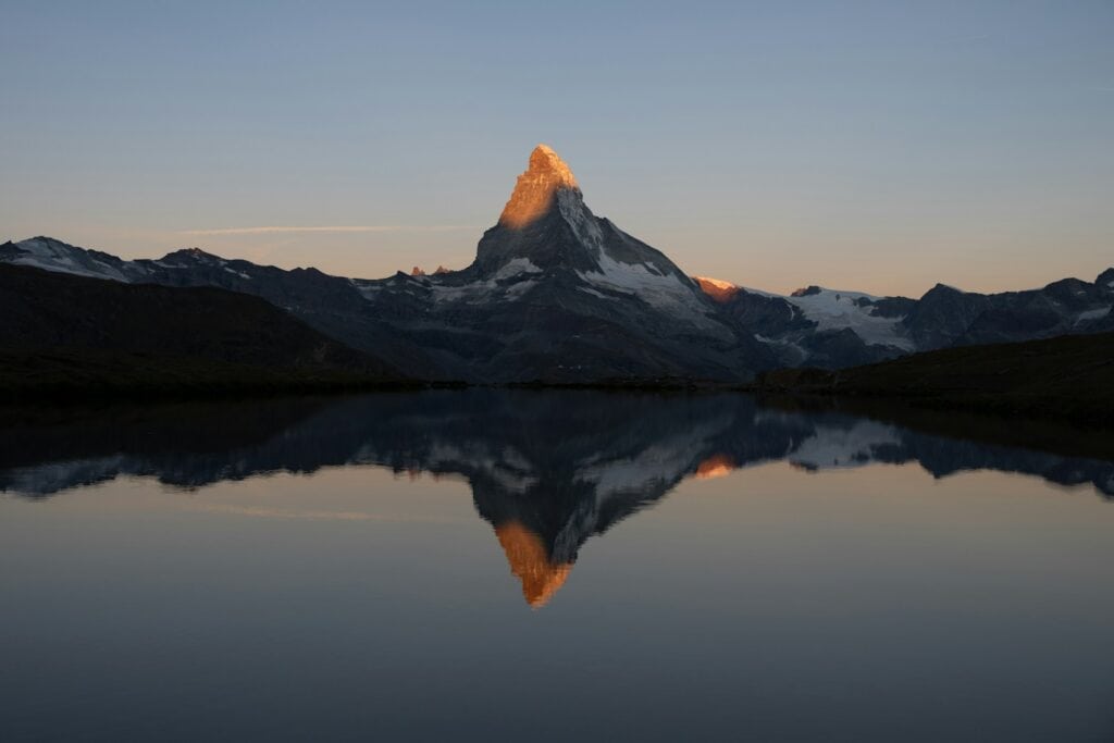 Majestic mountain peak illuminated by golden sunrise reflected sunlight.
