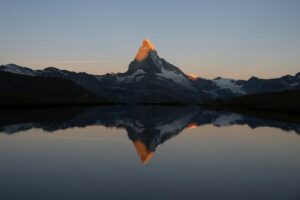 Majestic mountain peak illuminated by golden sunrise reflected sunlight.