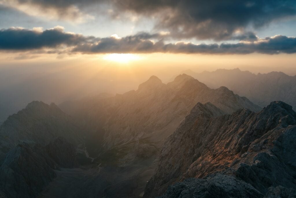 Sunbeams breaking through clouds over mountain peaks.