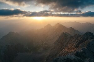 Sunbeams breaking through clouds over mountain peaks.